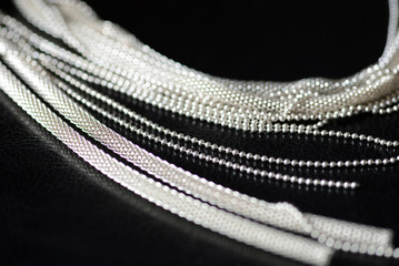 Metal necklace on a black leather surface close-up. Fashion and elegance concept