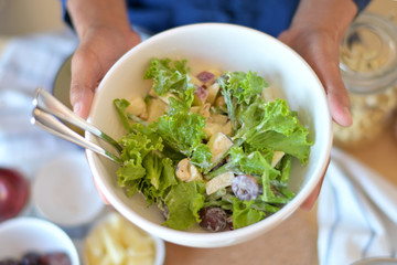 Asian men carrying dishes of fruit and vegetable salad in the kitchen