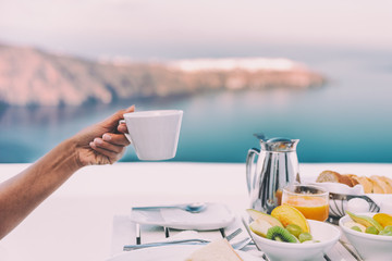 Drinking coffee cup at breakfast brunch table of cruise ship restaurant - luxury travel vacation getaway in Santorini - honeymoon destination.