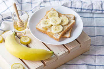 Breakfast homemade toast with banana and honey on wooden.