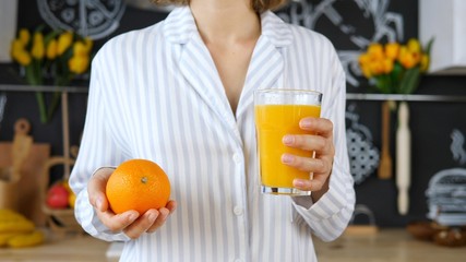 Young Female In Pajamas Holding Fresh Orange Juice In Hand