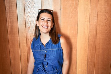 Young beautiful woman smiling happy and positive over wooden wall
