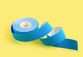 Blue kinesiology tape on a yellow background. Physiotherapy tape to relieve pain and tension.