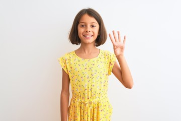 Young beautiful child girl wearing yellow floral dress standing over isolated white background showing and pointing up with fingers number four while smiling confident and happy.