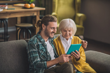 Grey-haired elderly woman looking at the tablet