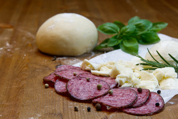 Dough basis and ingredients for pizza, on the wood table