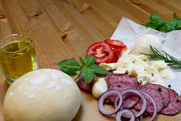 Dough basis and ingredients for pizza, on the wood table