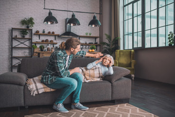 Naklejka premium Young man in jeans taking care of his sick mom