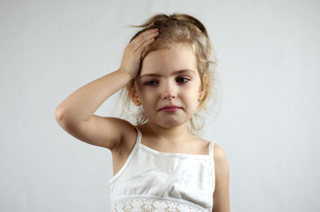 Little girl holds her hands on her forehead. Headache. Migraine