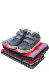 Stack of clothes, fresh laundry textile with shoes on top. Isolated on white background..