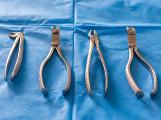 Dental pliers on a blue background. Concepts of dental care and dentist's office.