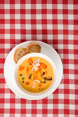 Tomato soup with mussel and pasta in a bowl on plaid tablecloth. Italian cioppino soup with bread. Top view copy space