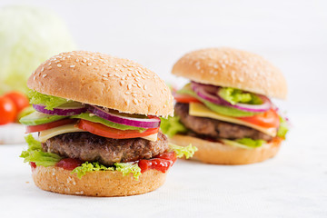 Big sandwich - hamburger burger with beef, avocado, tomato and red onions on light background. American cuisine. Fast Food