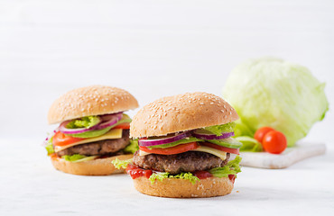 Big sandwich - hamburger burger with beef, avocado, tomato and red onions on light background. American cuisine. Fast Food