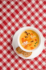 Tomato soup with mussel and pasta in a bowl on plaid tablecloth. Italian cioppino soup with bread. Top view copy space