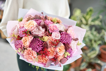 European floral shop. Beautiful bouquet of mixed flowers in womans hands. the work of the florist at a flower shop. Delivery fresh cut flower.
