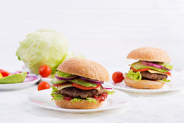 Big sandwich - hamburger burger with beef, avocado, tomato and red onions on light background. American cuisine. Fast Food