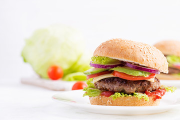 Big sandwich - hamburger burger with beef, avocado, tomato and red onions on light background. American cuisine. Fast Food