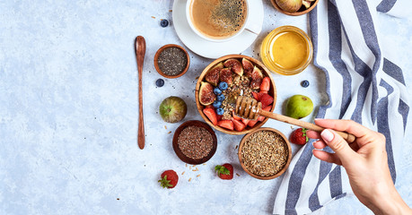 Top view showing hands eating porridge with honey, blueberries, strawberries on blue wooden table background Good morning, healthy breakfast background