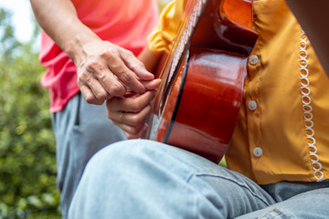 Man teaching his girlfriend to play guitar.