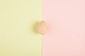One turkey egg on colored paper background. Food concept in minimal style. Top view. Alternative decoration.