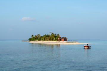 Landscape with a small island in the Maldives, Indian Ocean, Kaafu Atoll, Kuda Huraa Island. A motor boat is anchored in the foreground.