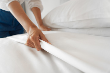 Female Hand set up white bed sheet in bedroom - obrazy, fototapety, plakaty