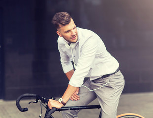 Obraz premium lifestyle, transport and people concept - young man with bicycle and headphones on city street