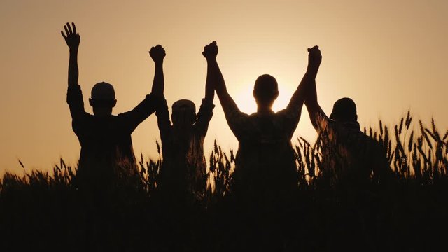 The team of farmers raise their hands up together in a sign of success and confidence in the team.