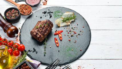 Baked veal steak with spices on a black stone plate. Pepper steak. Top view, free space for your text. Rustic style.