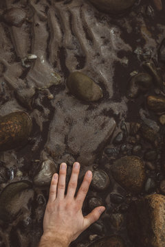 Male hand touching stones in water