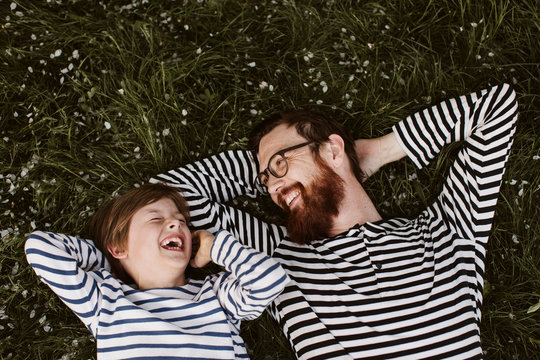 Father and son wearing similar stripped shirts lying on grass
