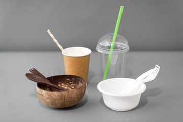 recycling, environment and eco friendly concept - close up of natural coconut bowl with wooden spoon and fork and plastic dishes on table