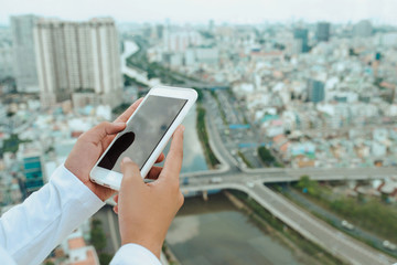 Woman uses Mobile Phone at cityscape background in morning light, close up
