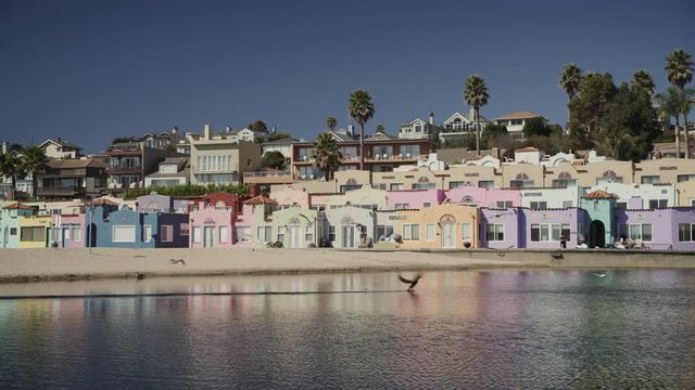 Birds flying on bay beach near multicolor houses / Capitola, California, United States