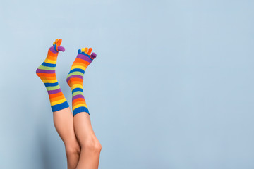 Funny playful woman legs wearing colorful socks over blue background