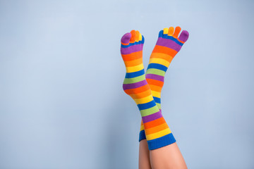Funny playful woman legs wearing colorful socks over blue background
