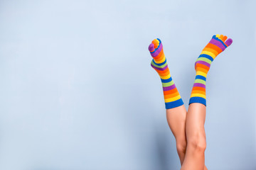 Funny playful woman legs wearing colorful socks over blue background