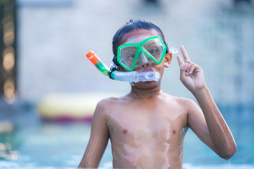 View of boy with swim glasses floating in the swimming pool