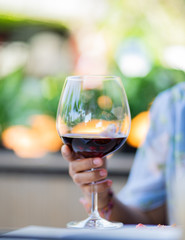 Someone holds a glass of red wine.