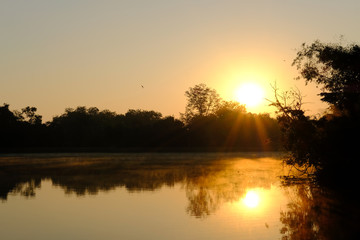morning sunlight & fog on lake pond with mountain view.