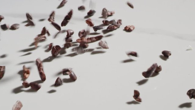 Cacao nibs sliding and bouncing across a countertop