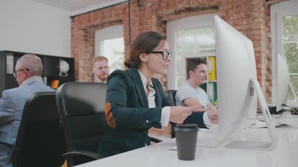Excited businesswoman pointing on computer screen drawing attention of colleagues