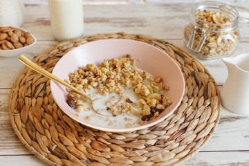 Granola with raisins and hazelnuts served with almond milk on a wooden table. Healthy breakfast.