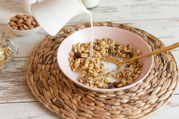 Granola with raisins and hazelnuts served with almond milk on a wooden table. Healthy breakfast.