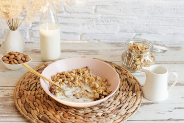 Granola with raisins and hazelnuts served with almond milk on a wooden table. Healthy breakfast.