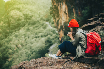 Happy hipster young girl with red backpack on peak mountain. Traveling alone concept.