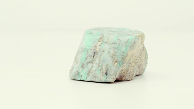 Extremely close view of roughly cut, green-blue Amazonite mineral chunk. Rotating back to front.