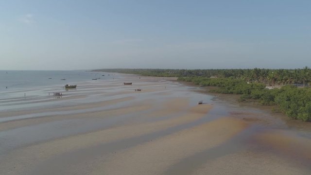 Scenic aerial push in shot of fisherman gathering at low tide on African beach