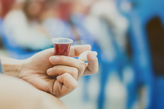 Hands hold a red wine cup in Holy communion